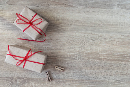 两个礼品盒用红丝带，两个衣夹上木背景