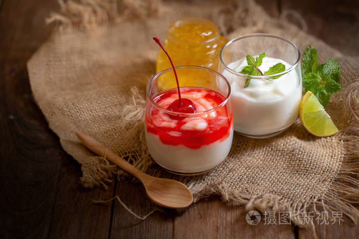 樱桃酸奶和薄荷柠檬酸奶在棕色木桌上的玻璃