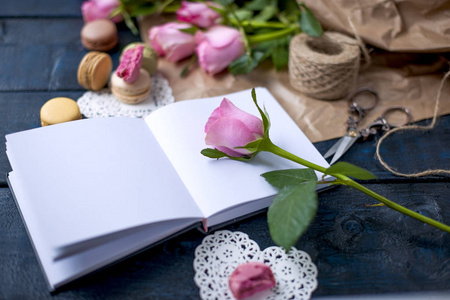 一束玫瑰是粉红色的, 灰色的纸和白色的心。玫瑰在打开的笔记本上。甜面食杏仁不同的颜色, 在情人节。免费的文本或广告场所
