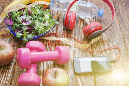 新鲜有机蔬菜与哑铃在木台面上, 饮食, 健康饮食的概念。耳机和电话。体育音乐