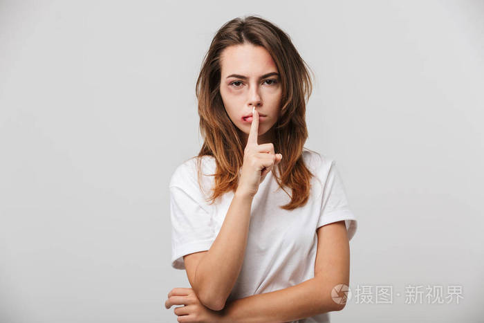 一个严重残疾的年轻女孩的照片, 她的脸上划伤和瘀伤显示沉默手势