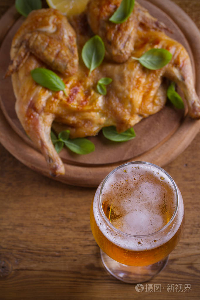 一杯啤酒和烤鸡肉.烤好的和多汁的鸡肉是喝啤酒的好食物.啤酒和肉类.