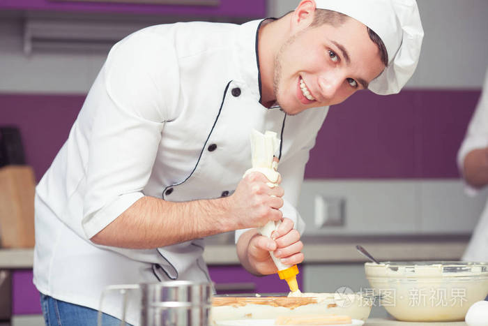 提拉米苏烹饪, 通过考试的概念。在现代厨房里做意大利甜点的厨师制服微笑的实习生肖像。室内拍摄