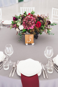 用红花花束装饰的婚礼桌和带餐具的灰色桌布