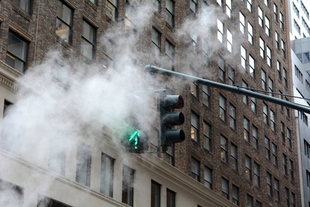 绿色箭头交通信号通过蒸汽发泄从街道