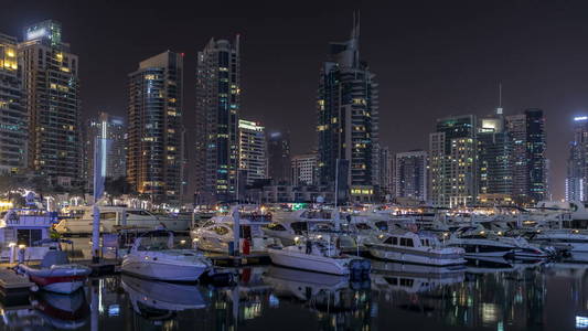 迪拜滨海湾与游艇 timelapse 船。夜晚照亮的摩天大楼反映在运河的水中