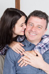 年轻夫妇在家里的沙发上亲吻表达他们的爱