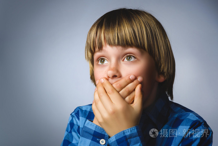 特写害怕和震惊的小男孩.工作室拍摄肖像在灰色的背景.