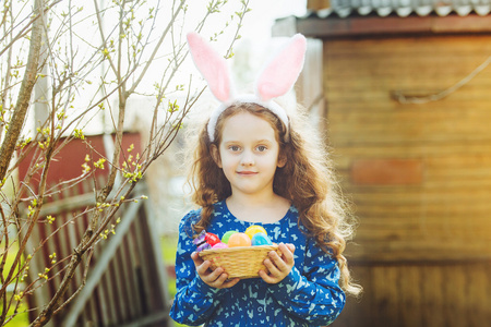 可爱的小女孩穿着兔子耳朵提着一篮与复活节彩蛋插画