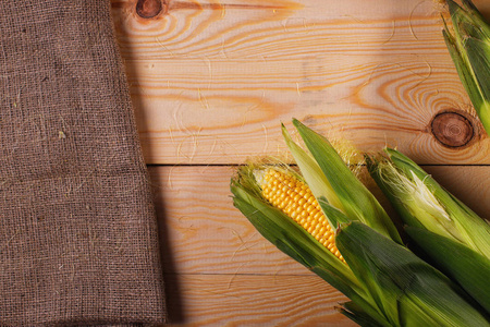 金色的玉米在一个木质的背景。粗麻布和玉米。顶部视图