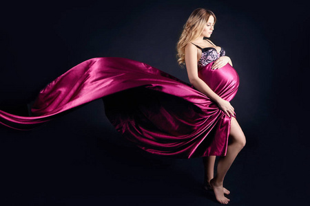 怀孕美女在内衣上的灰色背景的孕妇.在出生前的几天.