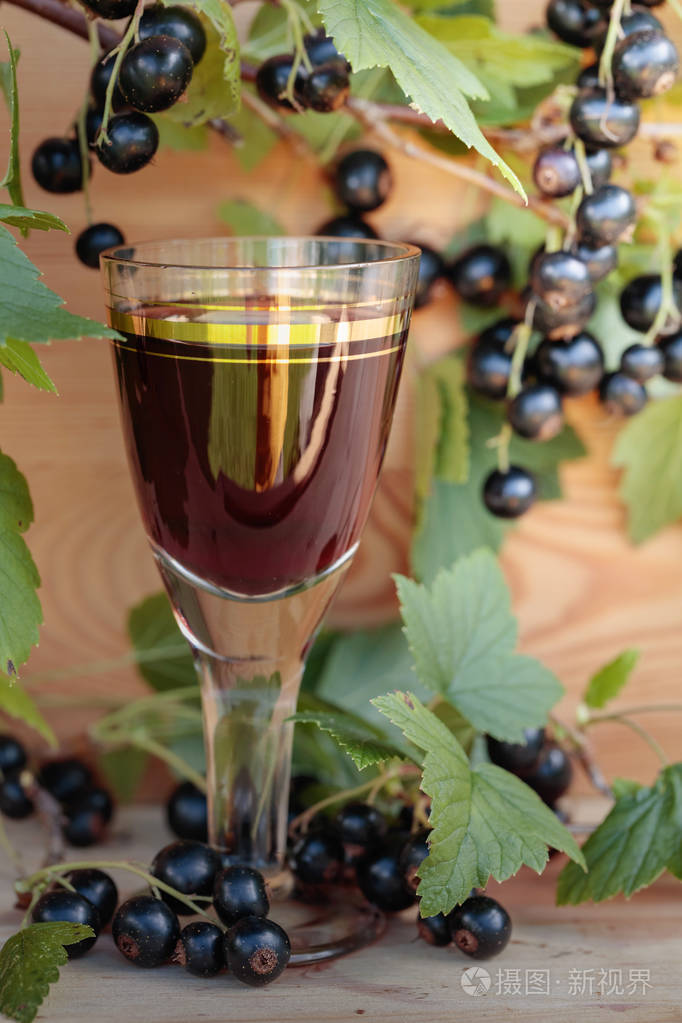 自制的甜酒由黑醋栗和新鲜浆果在树枝上老式木质背景