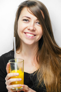 年轻妇女接近了肖像喝桔子汁。女模特幸福的微笑