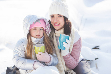 妈妈和女儿冬天在户外玩得很开心。漂亮的家庭喝茶和可可