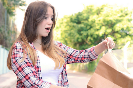 年轻漂亮的女人白色惊喜的脸拿着购物袋在户外。消费主义与生活方式概念