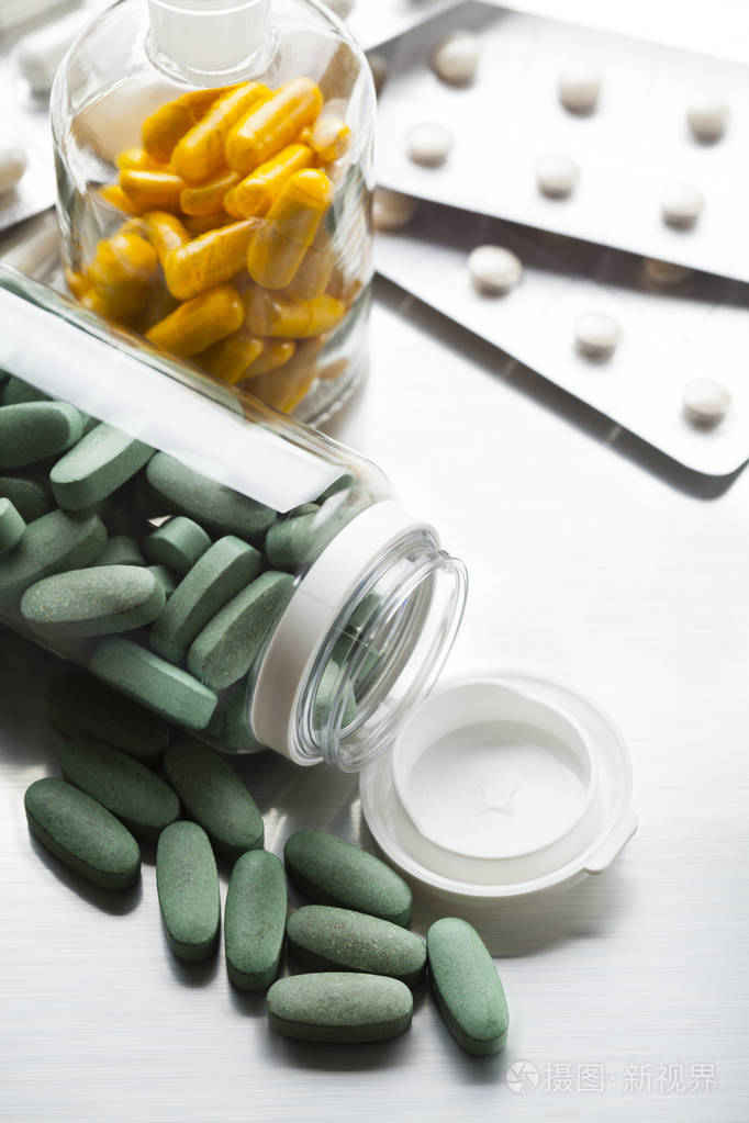 各种药物胶囊和药丸在灰色背景下