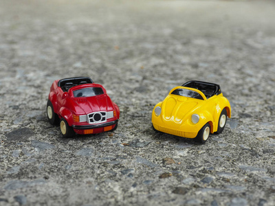 在粗糙的水泥路面上的红色和黄色的玩具汽车公园