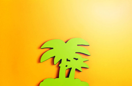 绿色棕榈树由树在柔和的橙色背景。平躺。夏季热带概念