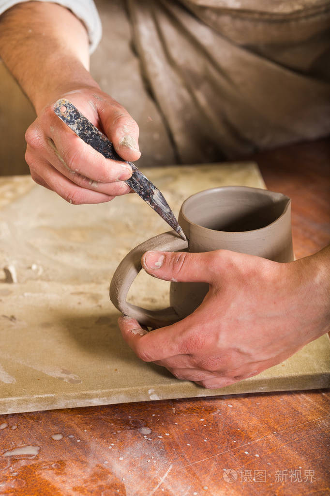 陶器, 石器, 陶瓷艺术概念-特写的工匠手连接句柄,杯子与工具,大师