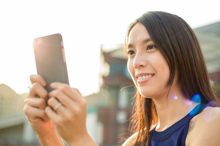 女人用手机在户外在日落时