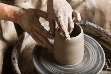 陶器 车间 陶瓷艺术概念关闭在男性手上雕刻一些新的器皿，用手指和水 个人手工作与陶工轮和原料粘土 顶视图