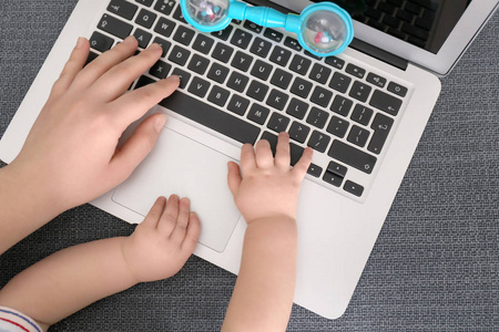 年轻的母亲与婴儿使用笔记本电脑