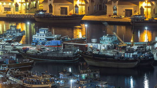 装货船在口岸说晚上 timelapse 在迪拜, 德伊勒河, 阿联酋。上面有许多旧船和路灯的空中俯视图