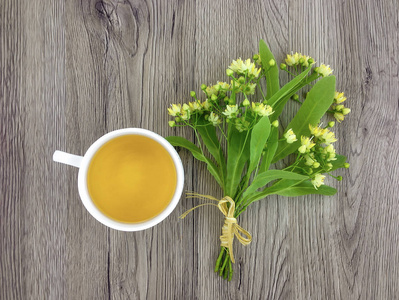 可爱束菩提树花和木制的桌子上的茶杯。平躺，顶视图