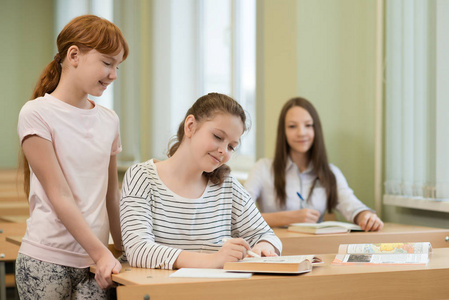 3学生女孩坐在桌旁