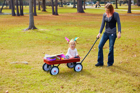 孩子们里程碑孩子们女孩和母亲走在公园与拉车照片
