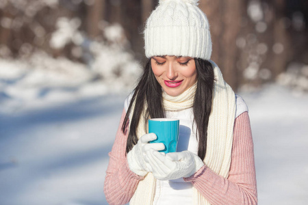 年轻迷人的妇女在户外喝咖啡在冬天时间