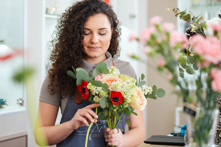 体贴的女子花店手捧鲜花，在店里制作花束