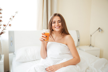 微笑女人在床上拿着桔子汁