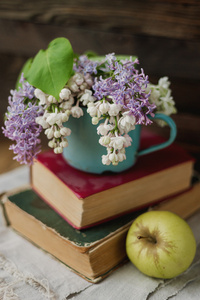 两本老书，苹果和生锈杯丁香花束上土布餐巾