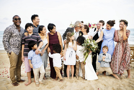 在海滩上成年夫妇的婚礼上多民族群体的客人