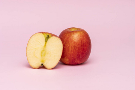 红色苹果整体和半片断在粉红色背景被隔绝了