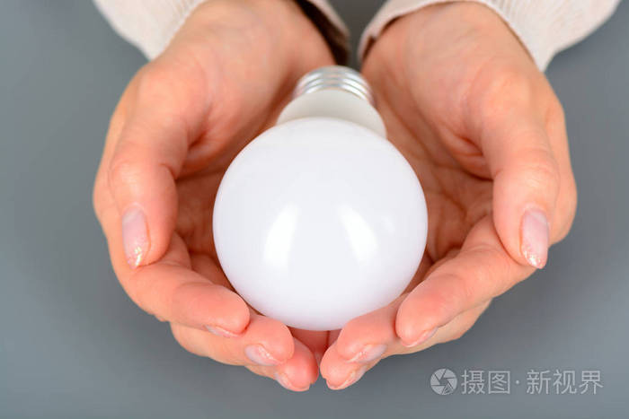 女性手里拿着一个 led 的灯泡