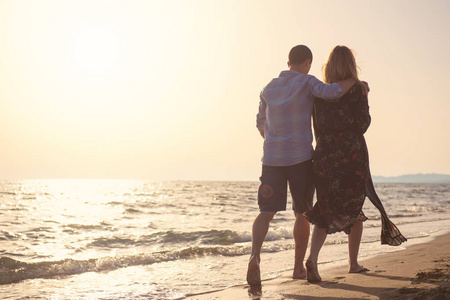 男人和女人在海边漫步日落, 后景色