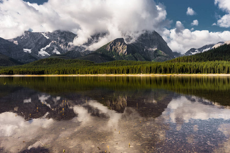 在彼得 Lougheed 省级公园卡纳纳斯基斯省 couds 的湖和山低悬挂的地方的倒影加拿大艾伯塔省