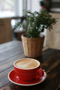 一个大的红色咖啡杯，木制的桌子上