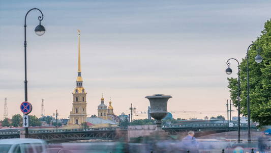 在彼得和保罗堡垒前面的 timelapse 和宫殿桥在俄罗斯圣彼得堡附近的河堤上的交通。多云蓝天的夏日