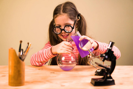 小女孩用化学器皿处理化学作业实验。儿童教育