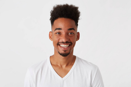 具有非洲发型的欢快诱人的黑人男子肖像穿 t恤 looka 快乐和微笑孤立的白色背景