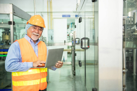年轻美丽的中国妇女在安全帽子摆造型和微笑与瓶灌装生产线在后台照片
