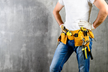 不知名的修理工用手在腰部和工具带与施工