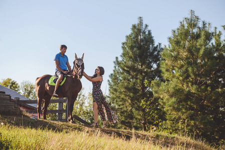 浪漫的爱，对年轻夫妇走在马背上，在自然背景上。一个女人触摸到一匹马。概念 爱 浪漫 爱好