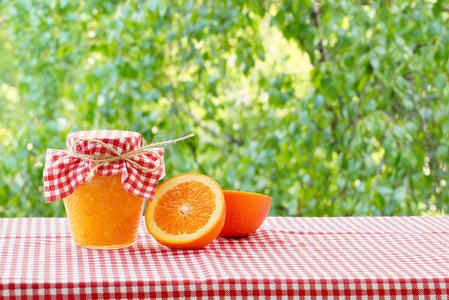 一罐橘子果酱和橙子红格子桌布图片