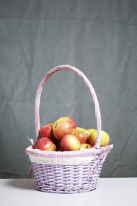 秋天收获的苹果。苹果从藤篮中的柳条上摘下。在灰色背景上