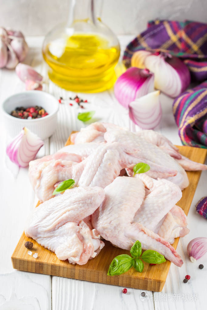 切板上的生鸡翅.烹调,香料,洋葱,油和大蒜配料