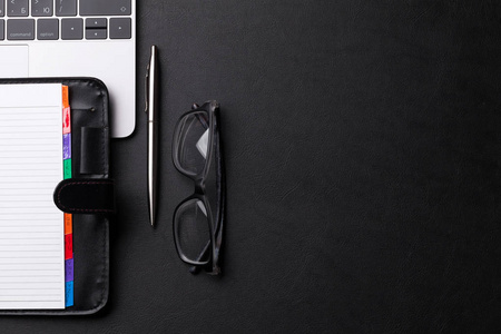 空白笔记本, 钢笔, 眼镜和笔记本电脑在黑色背景, 顶部视图与复制空间